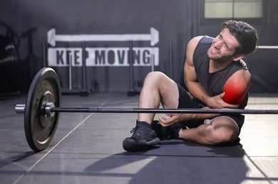 Sports injury chiropractor in Tulsa athlete with shoulder pain in gym needing chiropractic care